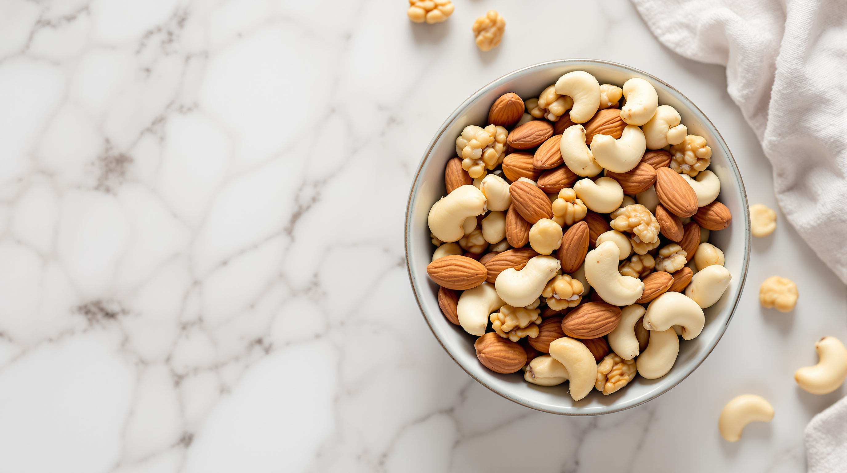 Schale mit gemischten Nüssen wie Mandeln, Walnüssen und Cashews auf einer hellen Marmoroberfläche